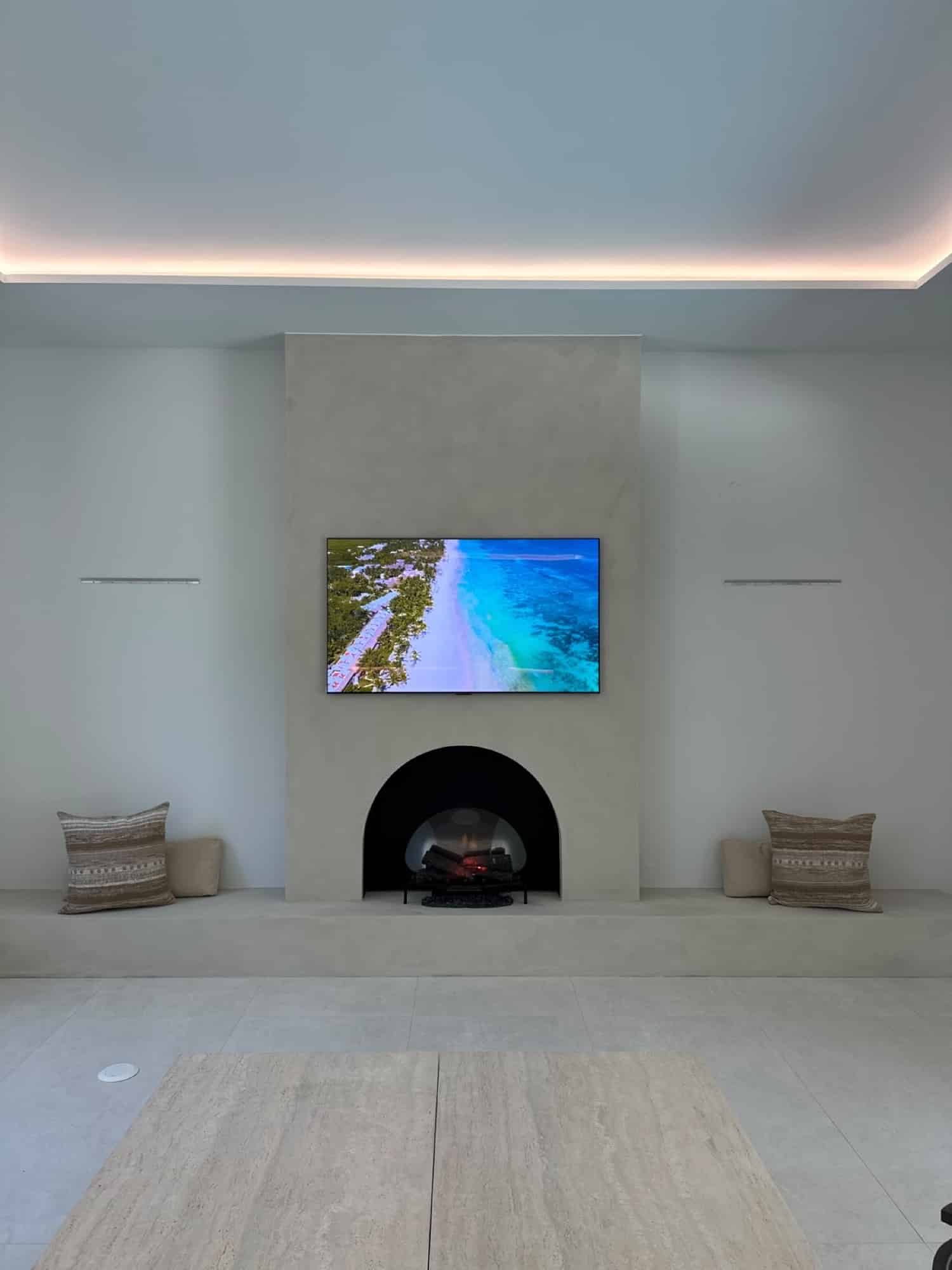 TV Wall Studio custom arched plaster fireplace wall in a bright Florida living room