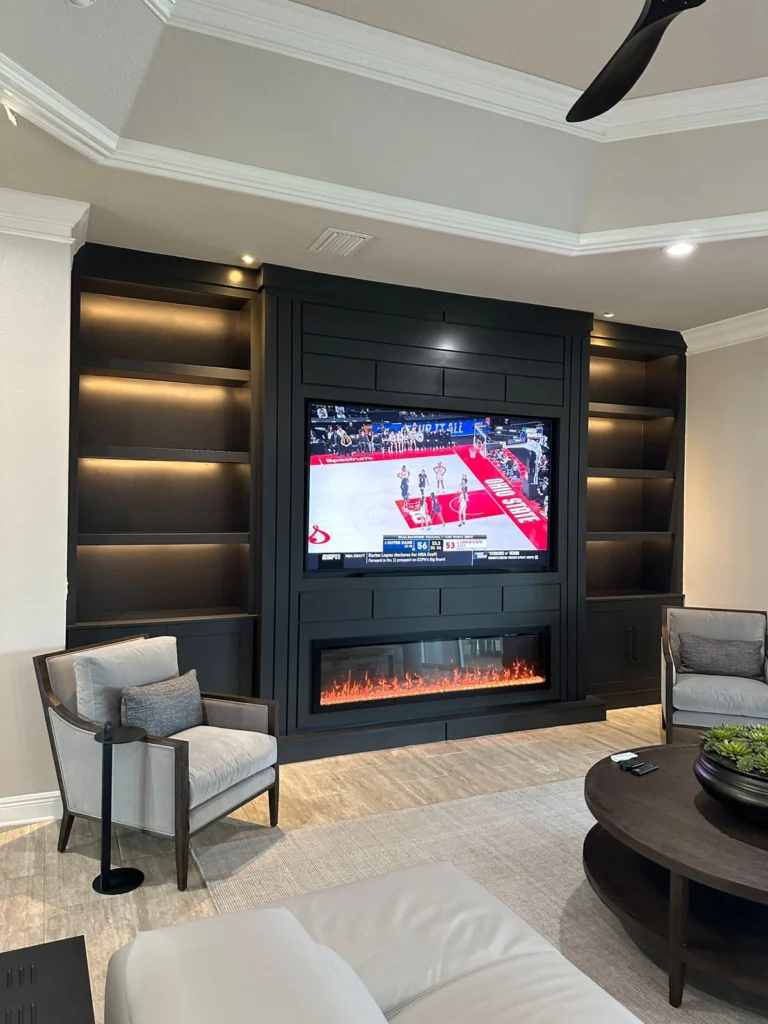 Dark charcoal fireplace media wall with warm illuminated shelves