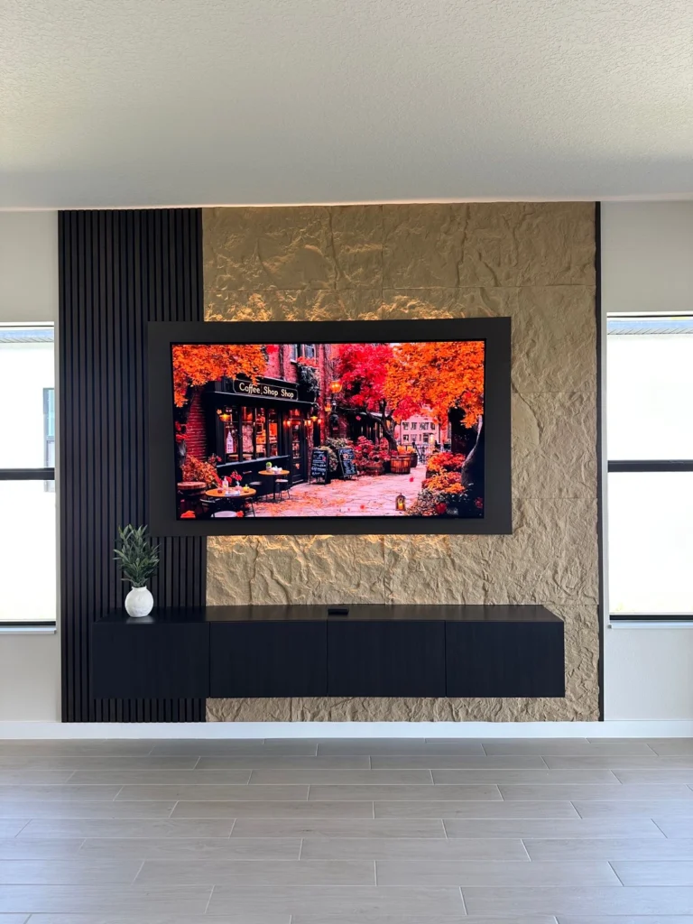 Completed floating TV wall with black wood slats, textured stone and floating media cabinet in a Florida home