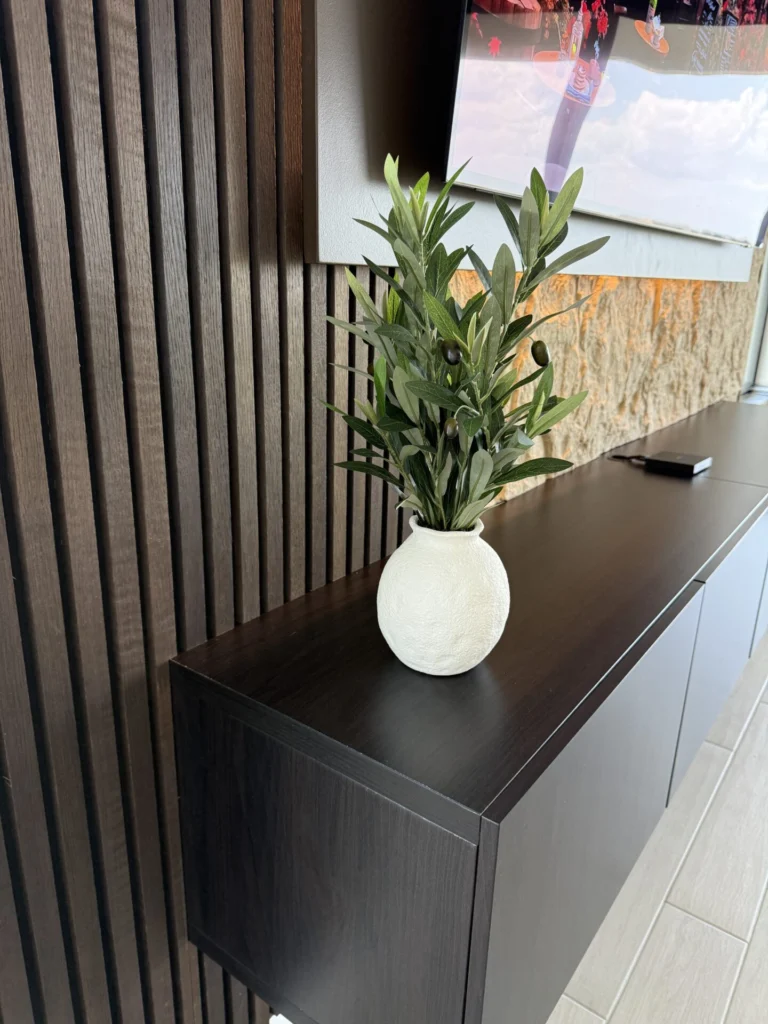 Black floating media cabinet beneath decorative wood slats