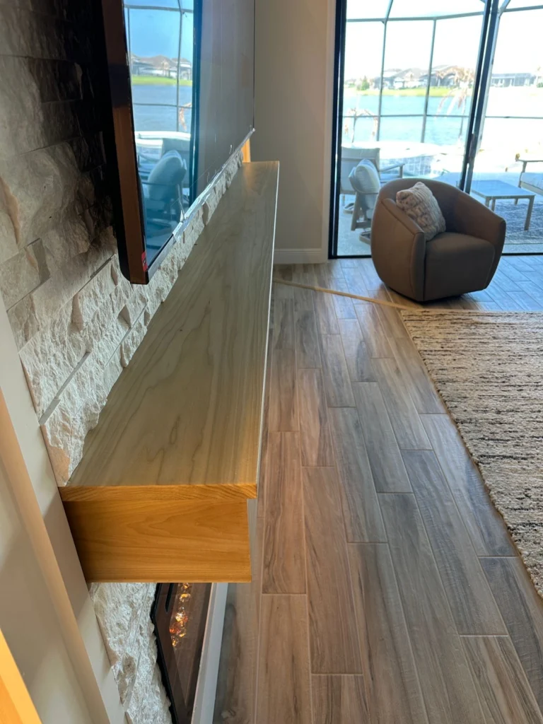Solid wood floating mantel detail on a stone fireplace wall