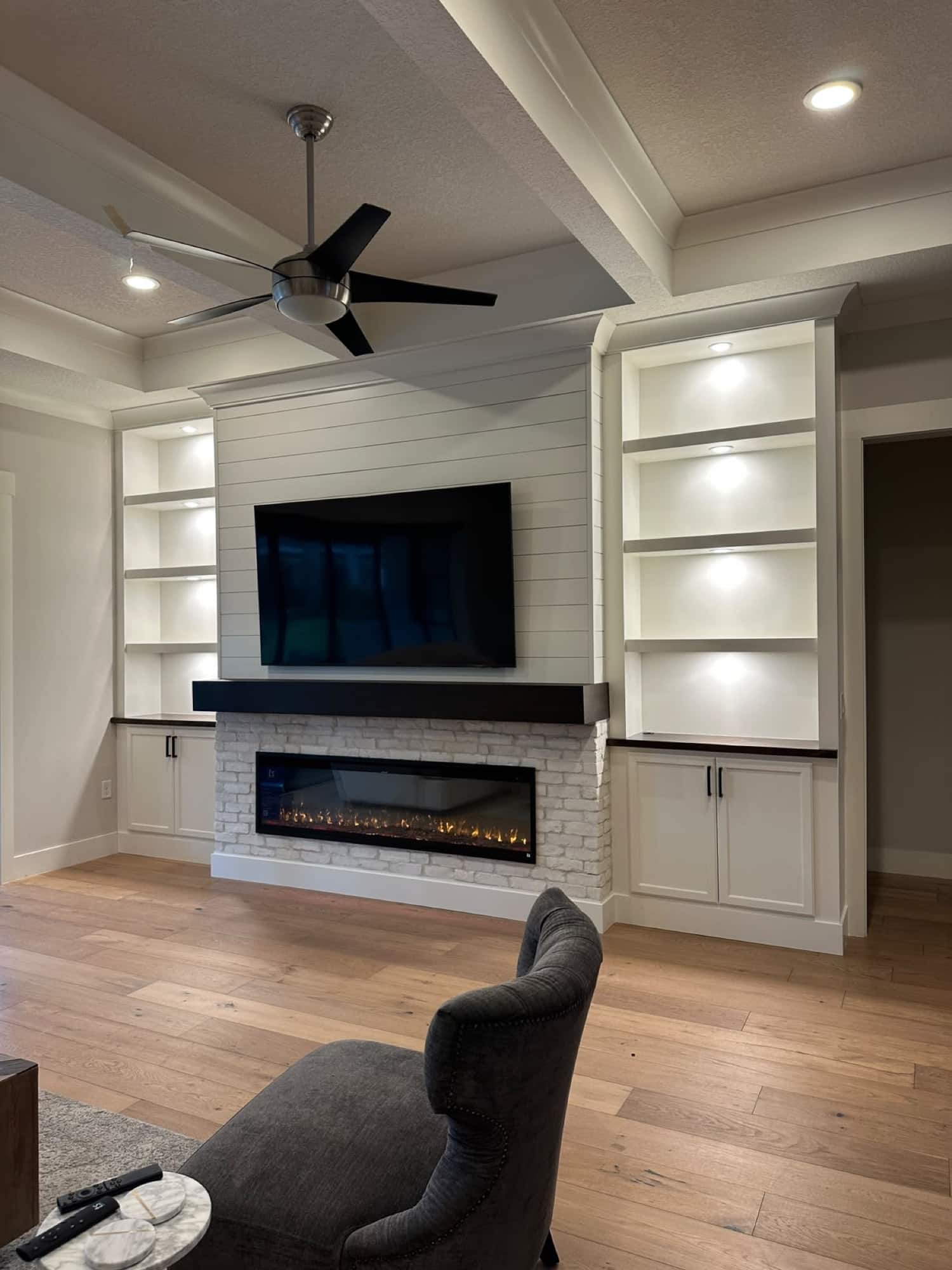 Florida fireplace wall with built-in shelving White brick fireplace wall with illuminated built-ins installed in Florida