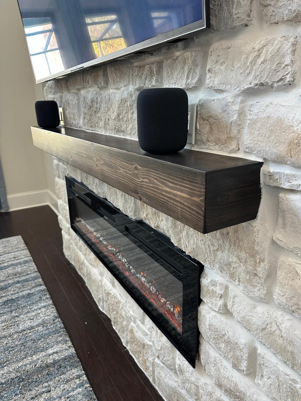 Close detail of a handcrafted dark wood mantel installed across a natural limestone fireplace wall
