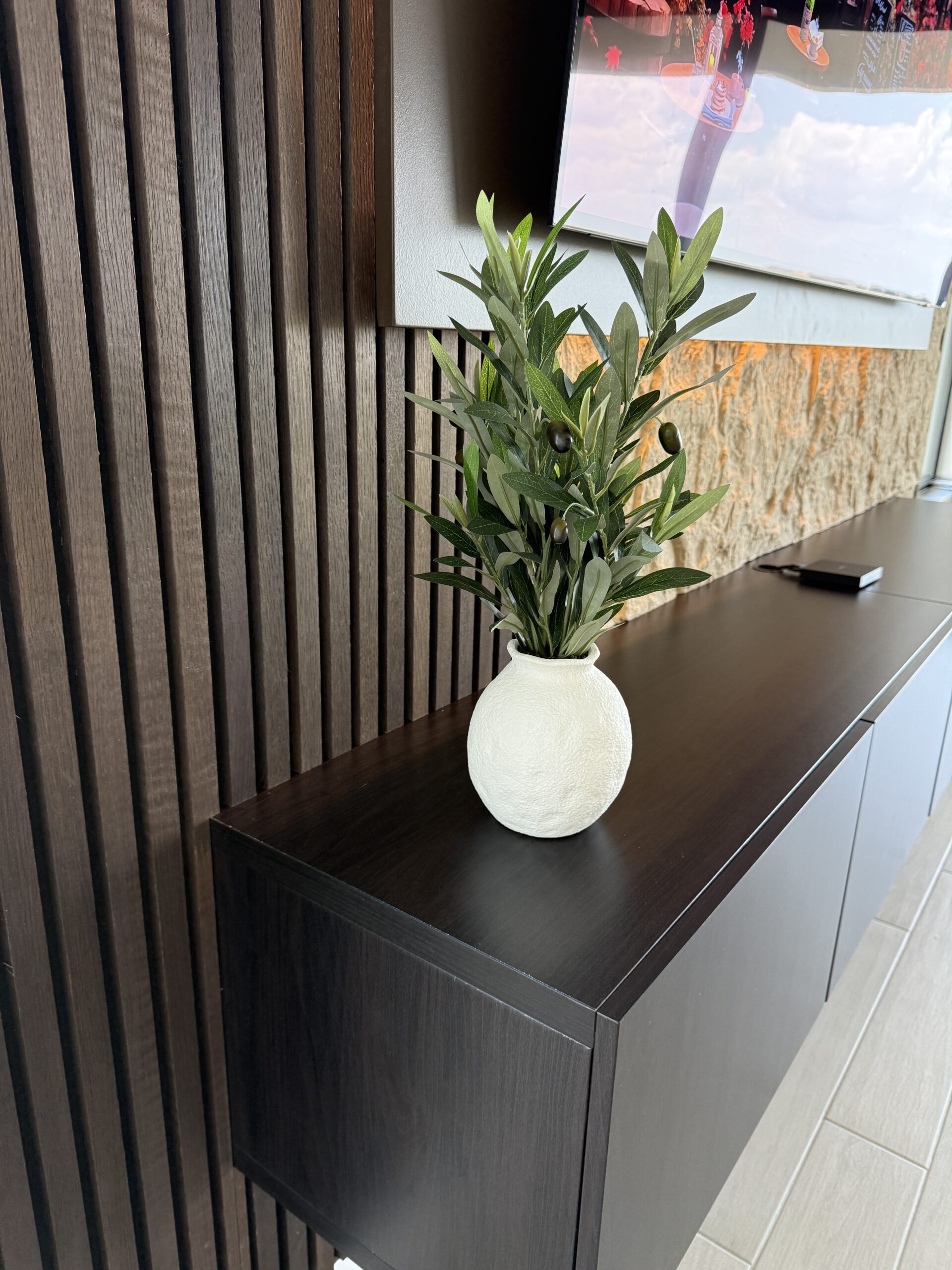 Close-up of the floating cabinet, dark slat panel and layered television surround