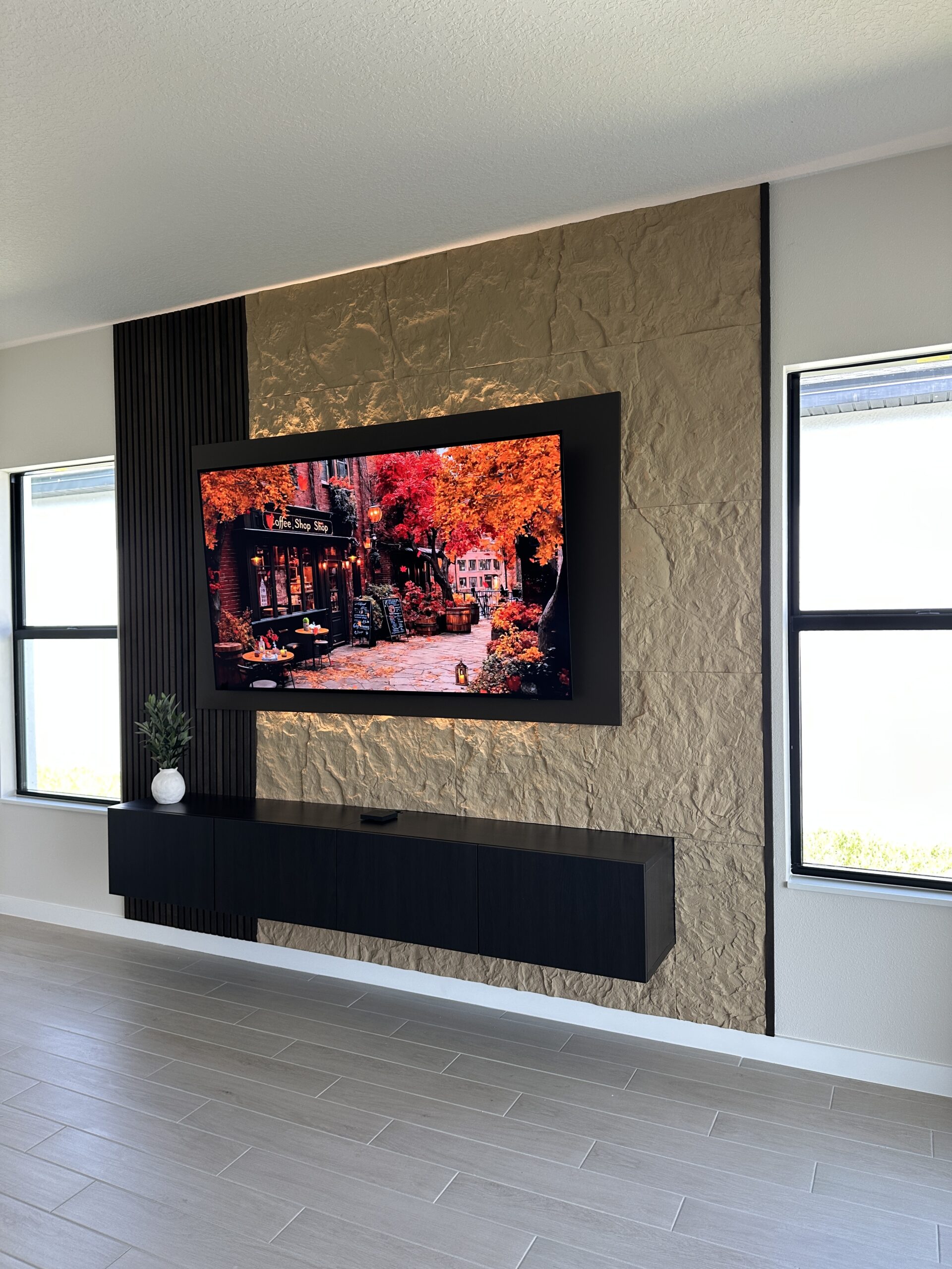 Custom floating media cabinet integrated into a complete TV wall Complete Florida TV wall with a five-door floating media cabinet, light textured panels and a dark slat accent