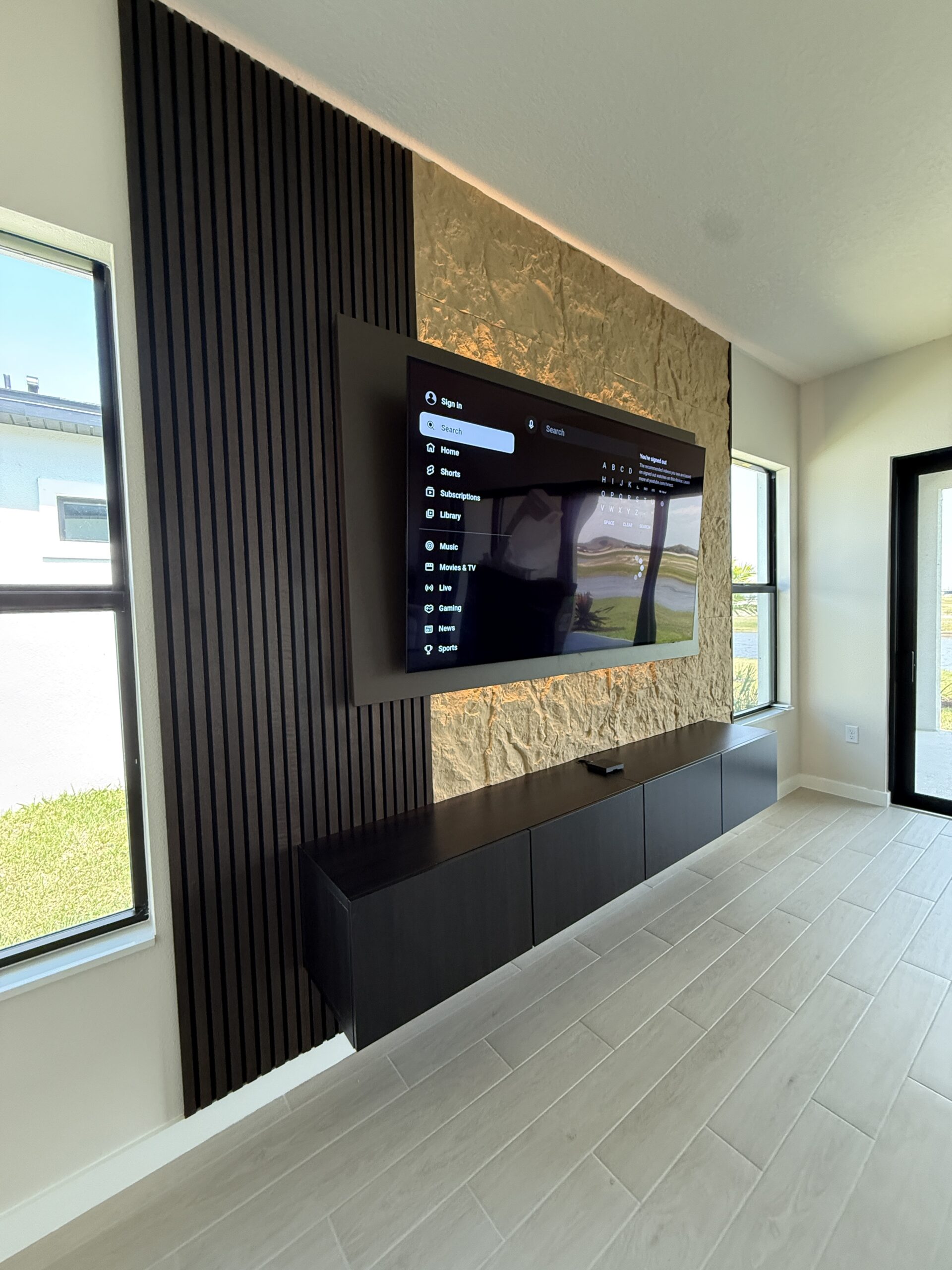 Opposite angle of a complete TV wall showing the five-door floating cabinet and open floor reveal